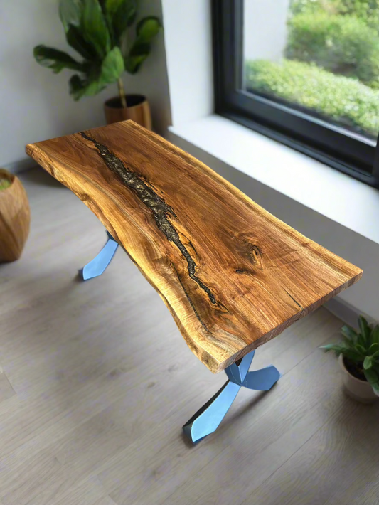 Black walnut table with bronze epoxy, sitting on black legs next to a window and plants